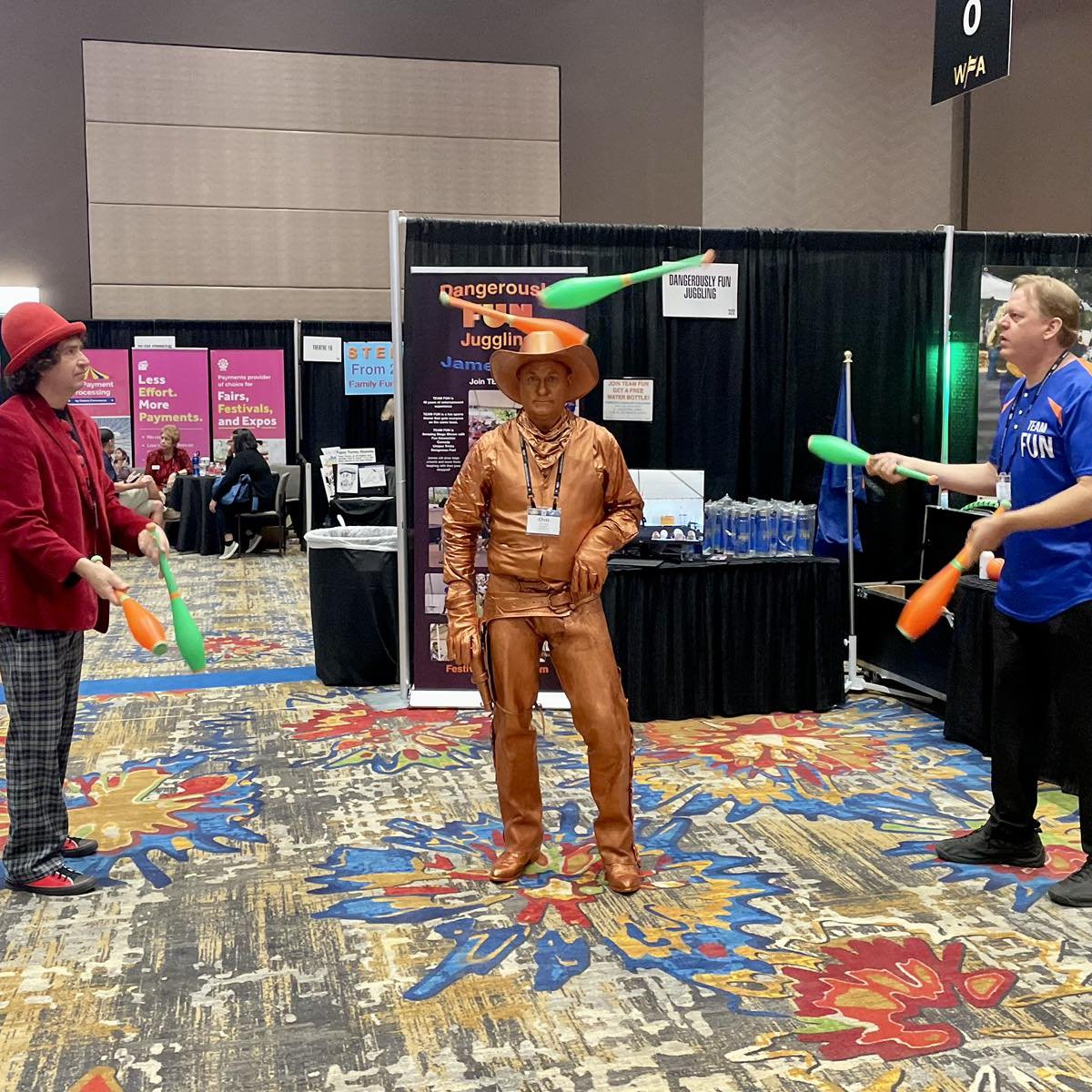 Marcus Wilson juggles at a live event alongside a human statue and fellow performer